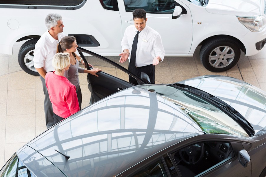 View of car salesman showing vehicle to family