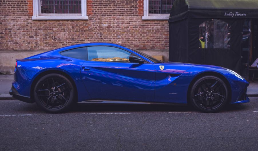 A blue Ferrari F12 Berlinetta parked on the street.