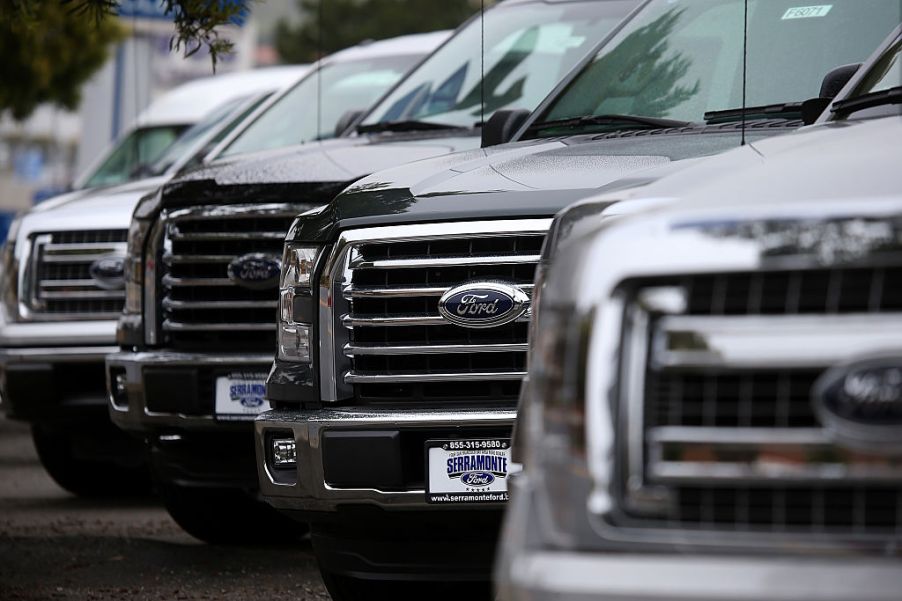 A line of new Ford F Series trucks at a dealership.