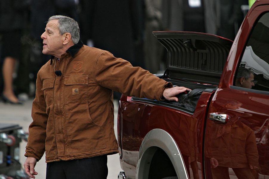 A man opening a storage compartment on the side of his pickup truck.