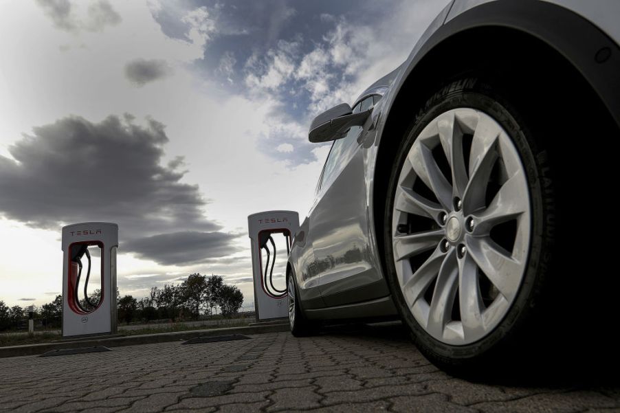 A Tesla car sits parked at a supercharger