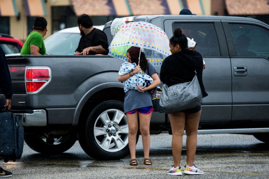 A young family stands around an expensive pickup truck.