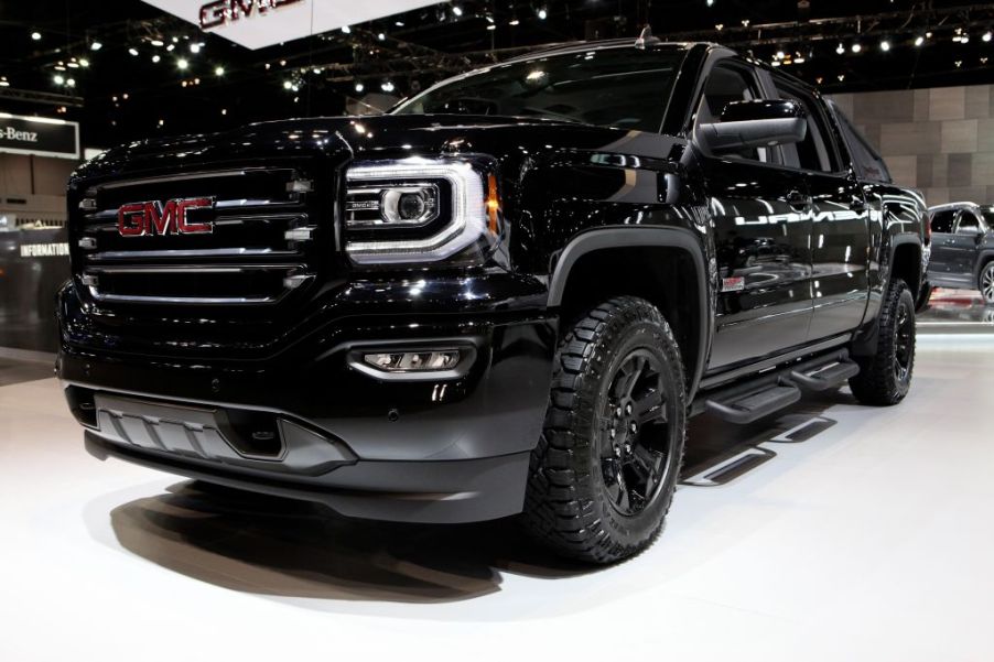 A black GMC Sierra pickup truck on display at an auto show.