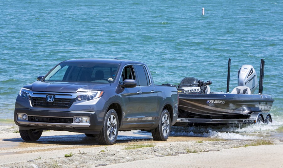 A gray 2020 Honda Ridgeline towing a boat through sand.