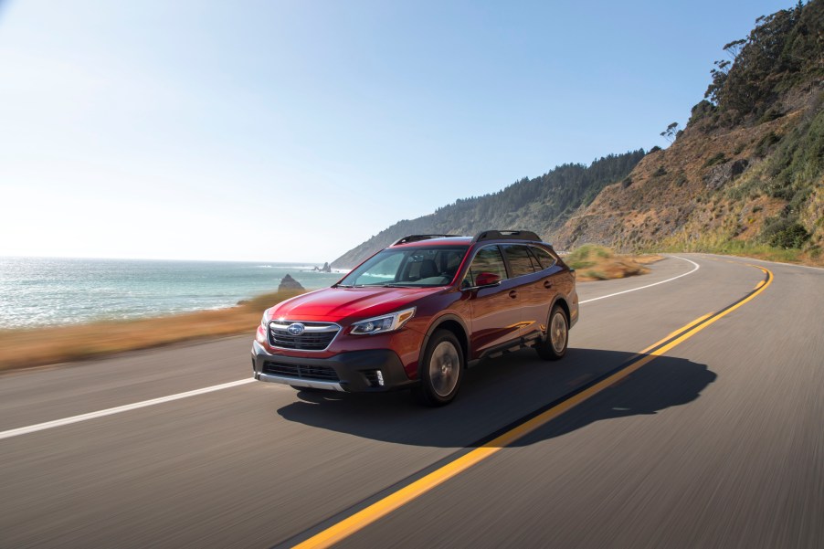 A red 2020 Subaru Outback driving on the countryside.