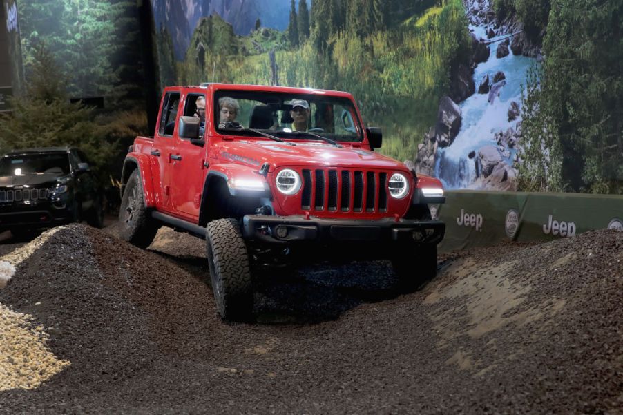 A person testing driving a Jeep Wrangler Rubicon at an auto show