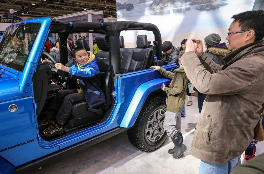 A family checking out a Jeep Wrangler SUV at an auto show