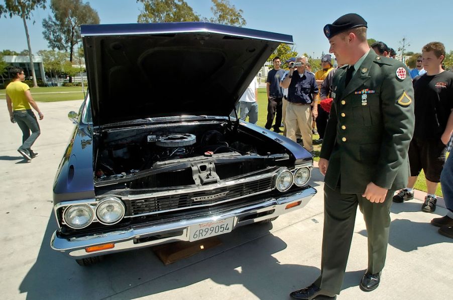 A solider walking by to check out a Chevy El Camino truck