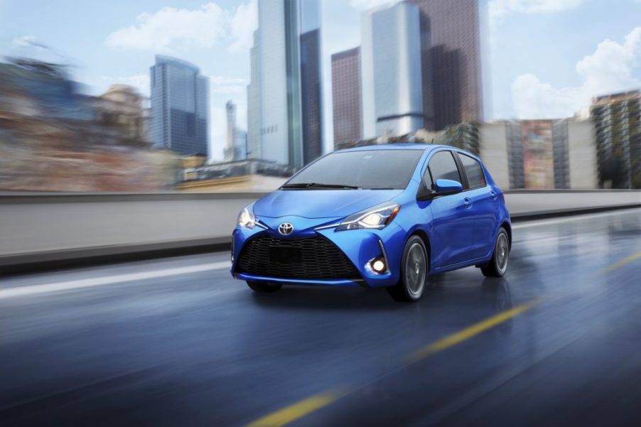 a blue Toyota Yaris driving though a rainy city