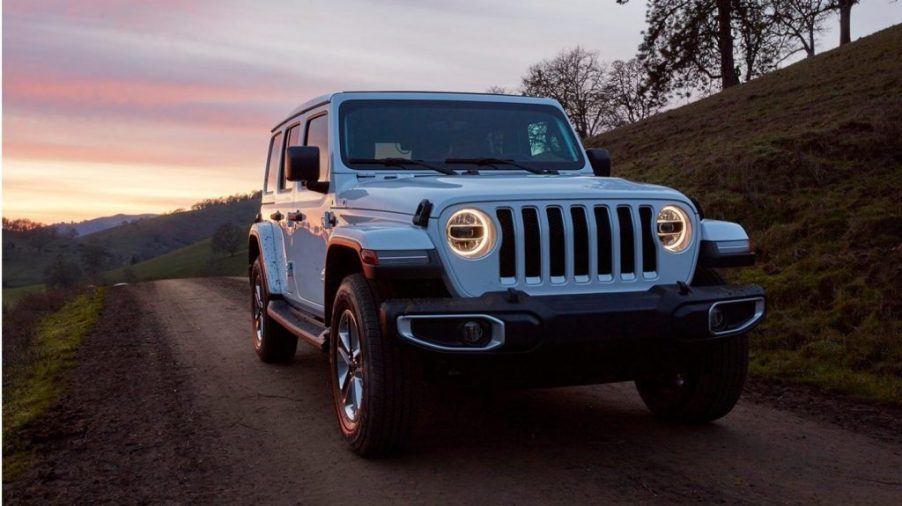 popular Jeep Wrangler off-road SUV driving at night with its lights on