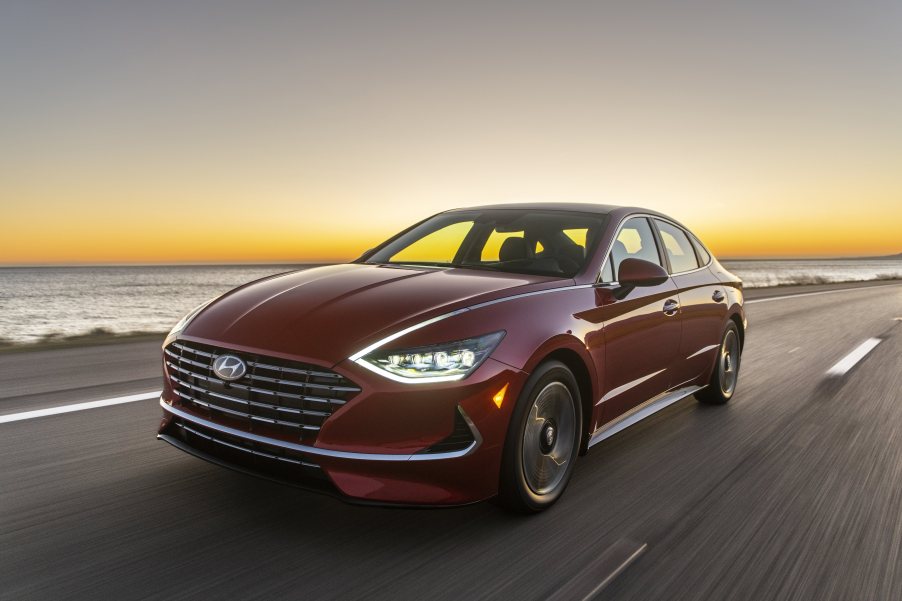 a red redesigned Hyundai Sonata at speed on a road near the water