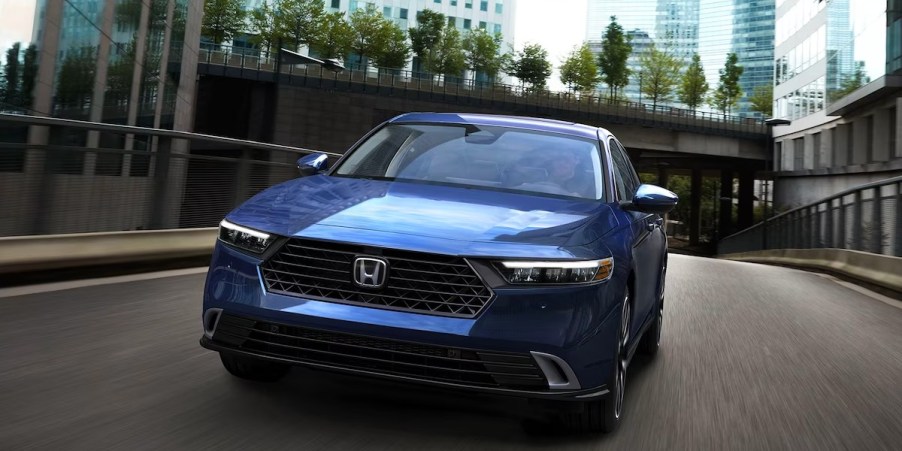 A blue Honda Accord midsize sedan is driving on the road.