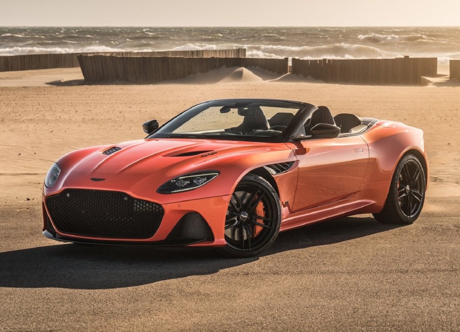 Orange 2020 Aston Martin DBS Superleggera Volante with the top town in front of the beach