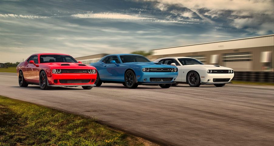 Three 2020 Dodge Challengers, red, white, and blue are on the track side by side.