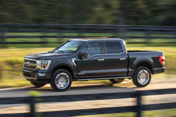 A black 2021 Ford F-150 rides on a dirt road.