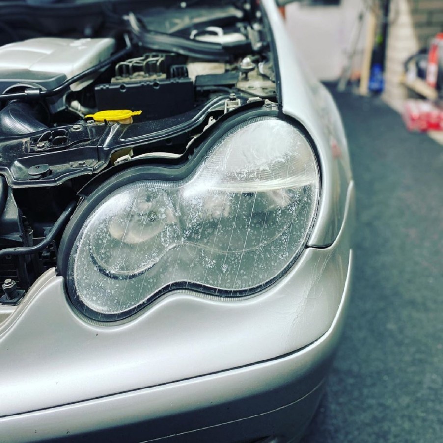 Gray Mercedes-Benz with foggy and clouded-over headlight lenses in a shop