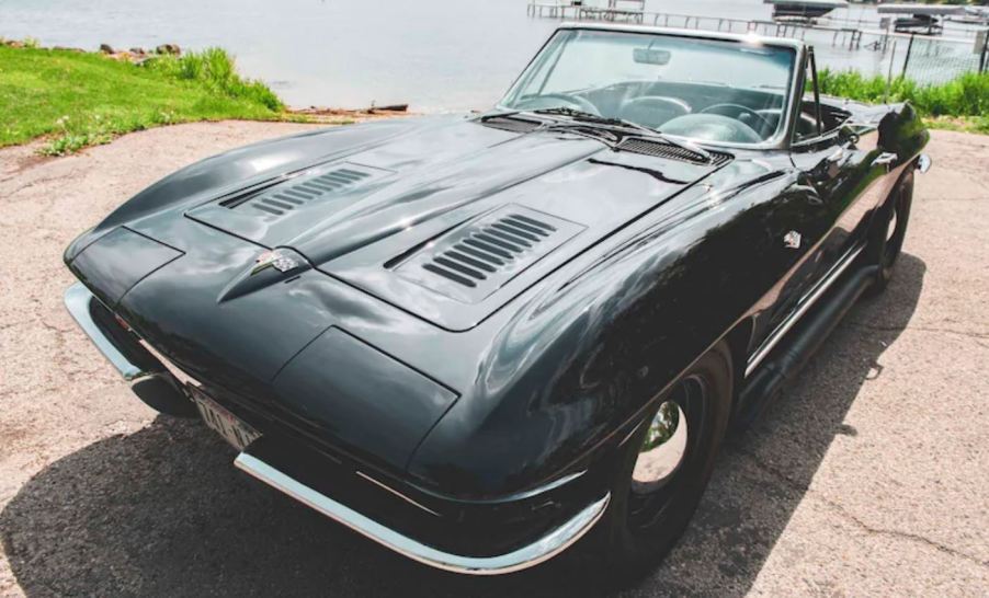 A black 1963 Chevy Corvette Sting Ray Convertible by a pier.