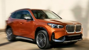 An orange BMW X1 subcompact luxury SUV is driving.