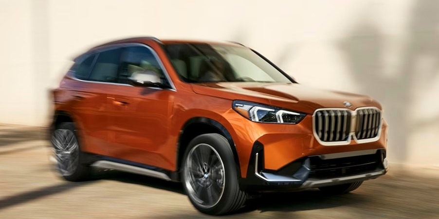 An orange BMW X1 subcompact luxury SUV is driving.