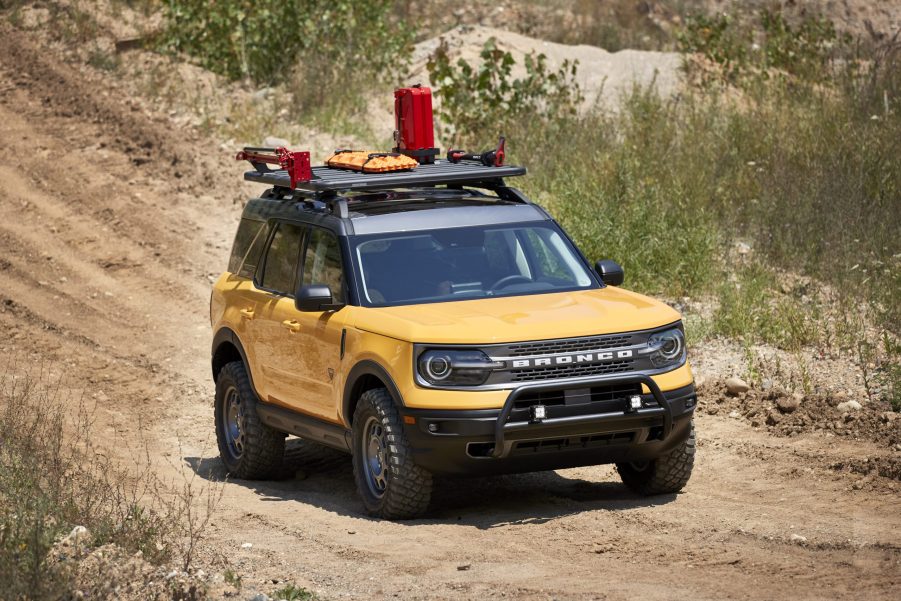 A yellow 2021 Ford Bronco Sport with a roof rack and bump guard travel a dirt road.