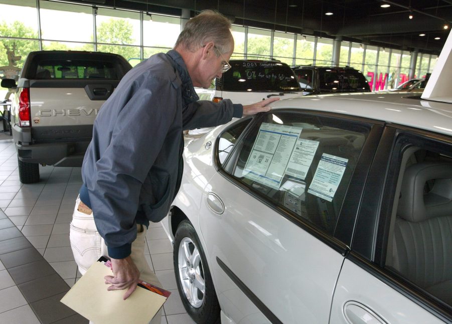 Car Sales: A man inspects a car inside a dealership