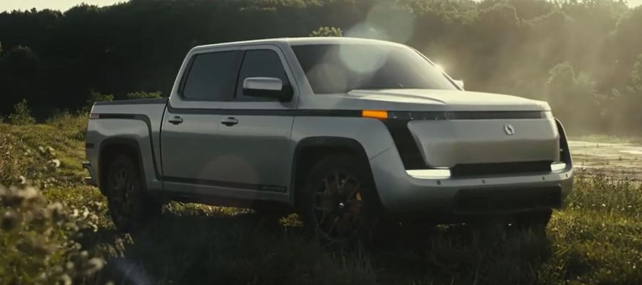 A silver 2021 Lordstown Motors Endurance pickup sits in a field on a sunny day.