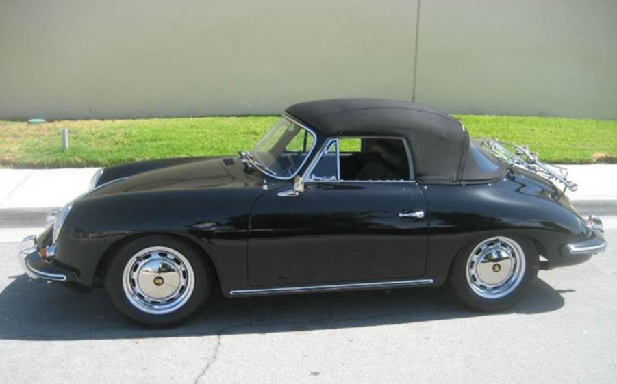 A black 1965 Porsche 356 SC Cabriolet sit by a curb with its black convertible top up.