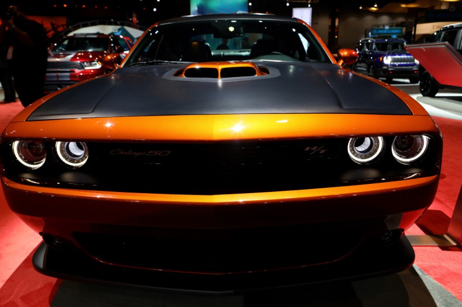 An orange Dodge Challenger on display at an auto show