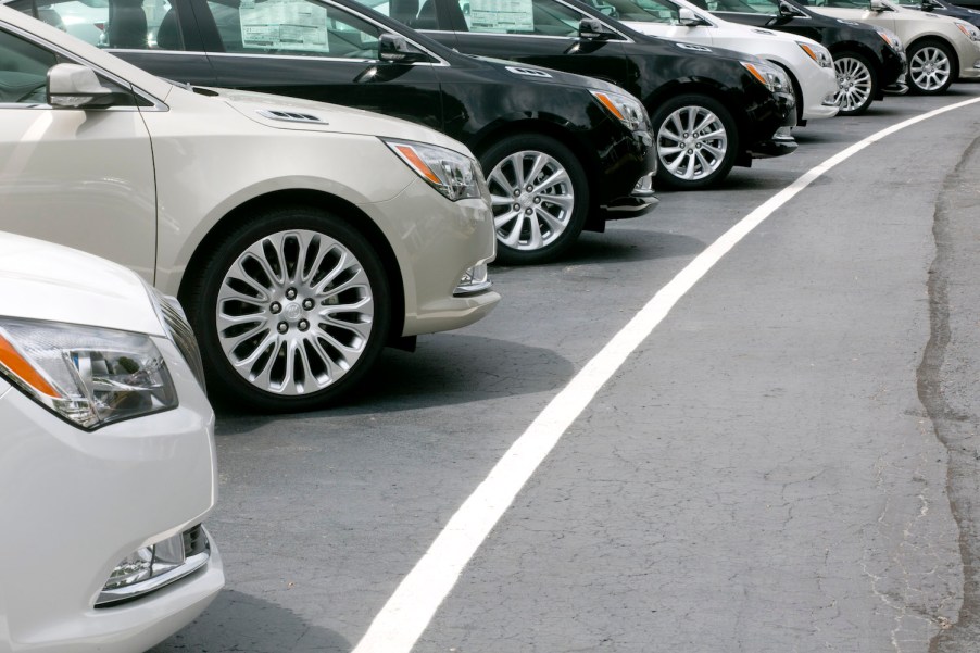 A row of sedans in a parking lot at a car dealership.