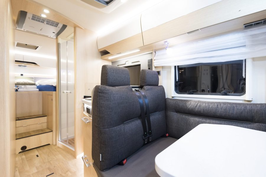 Interior view of a table, shower, and bed area in a HYMER camper van.