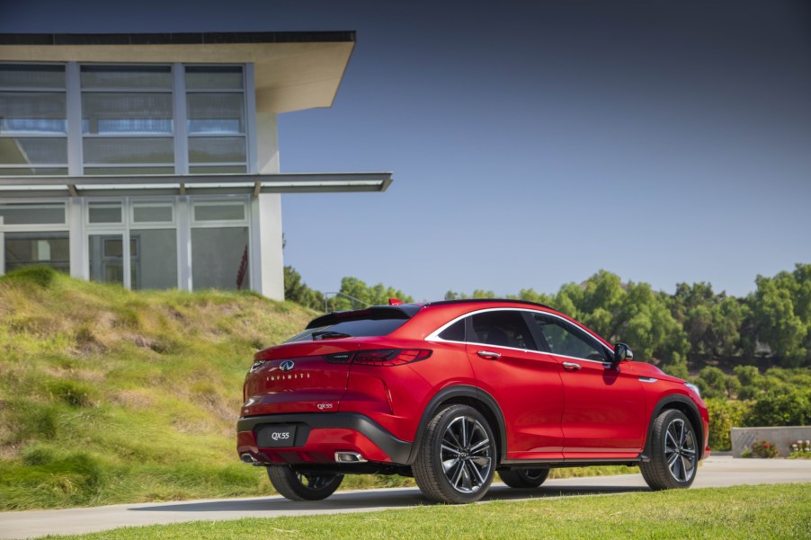 A red 2022 Infiniti QX55 driving away from a building