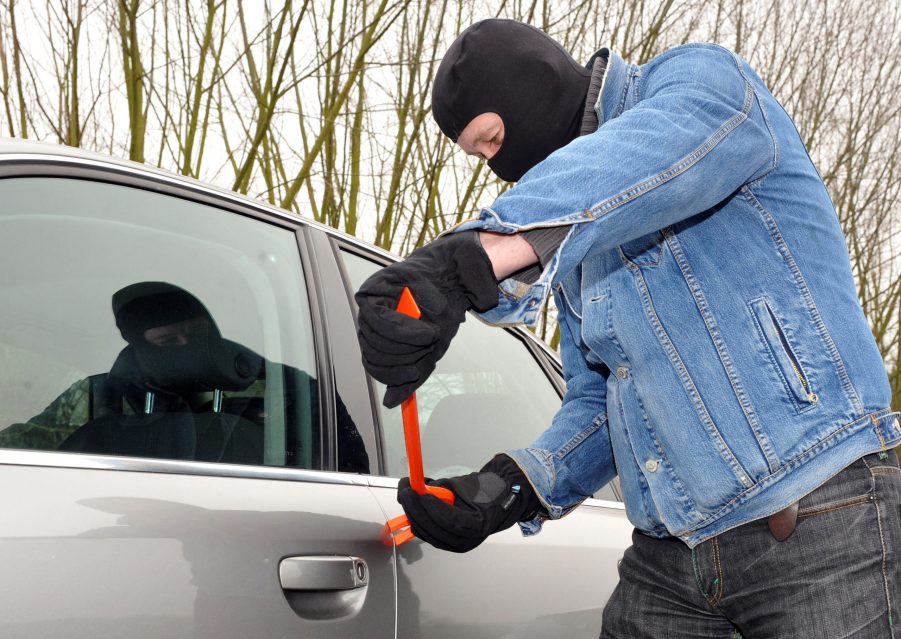 a man with a black mask breaking into a car