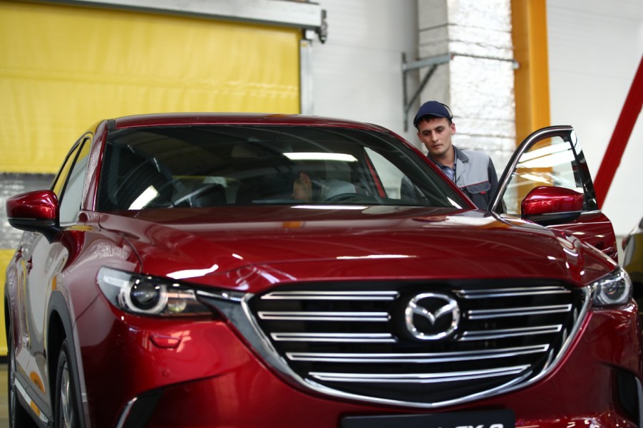 A man inspects a red Mazda CX-5