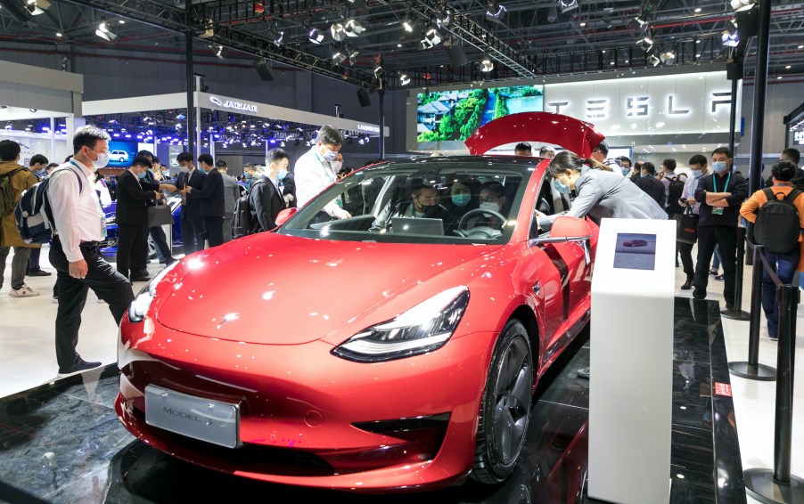 People view a Tesla Model 3 electric car at the auto exhibition area of the third International Import Expo