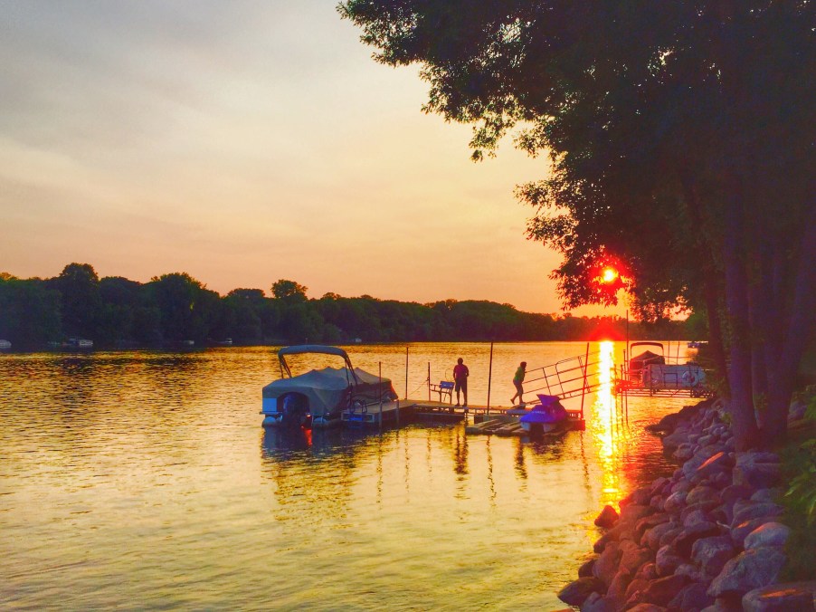 Couple walking on a dock next to a docked pontoon boat on the Mississippi River MN in July 2015.