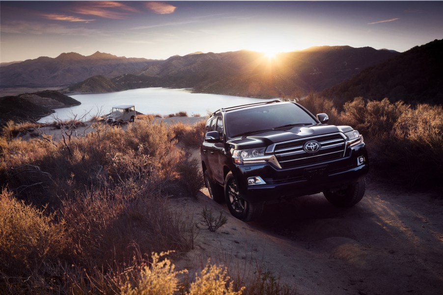 A 2020 Toyota Land Cruiser climbs a hill next to a lake.