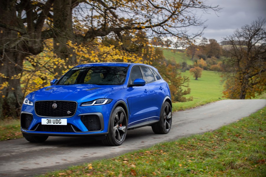 A blue 2021 Jaguar F-Pace SVR driving down a road near a tree