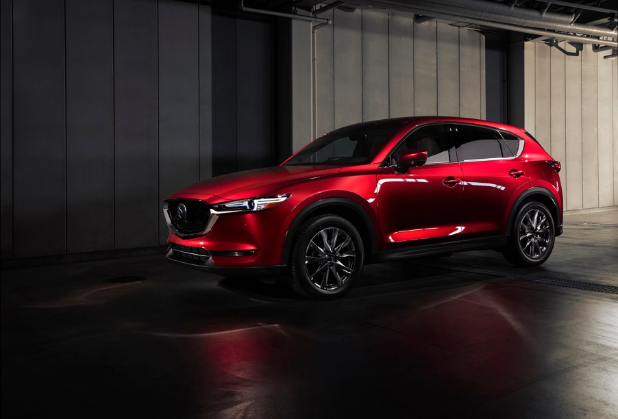 A metallic red 2021 Mazda CX-5 is parked next to a gray concrete building