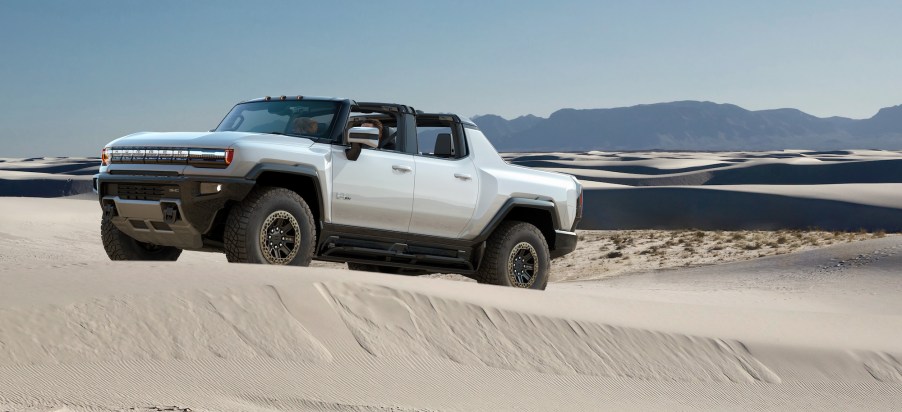 A white 2022 GMC Hummer EV truck drives dessert dunes