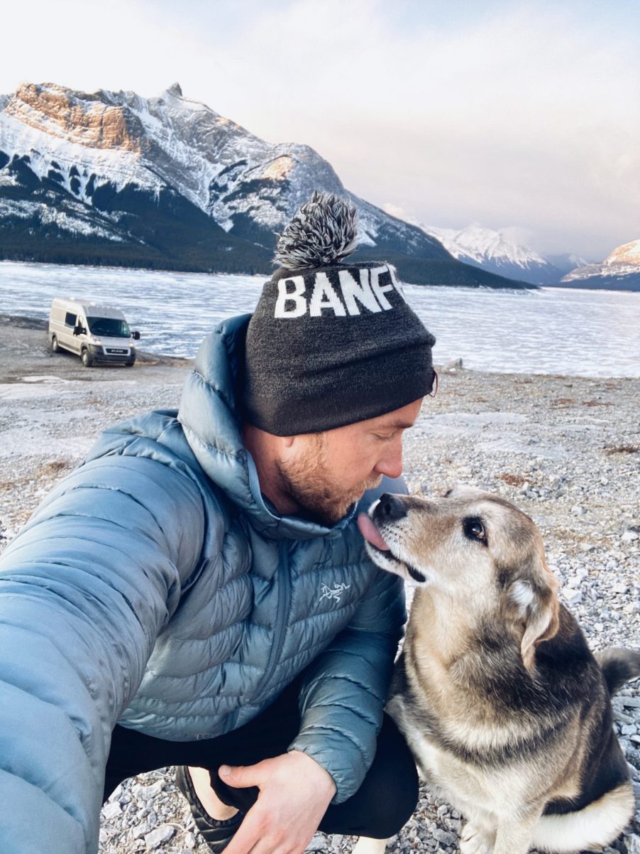 Bear Bear and Dietrich enjoying a moment outdoors with the dodge promoter camper van behind them near a beautiful lake