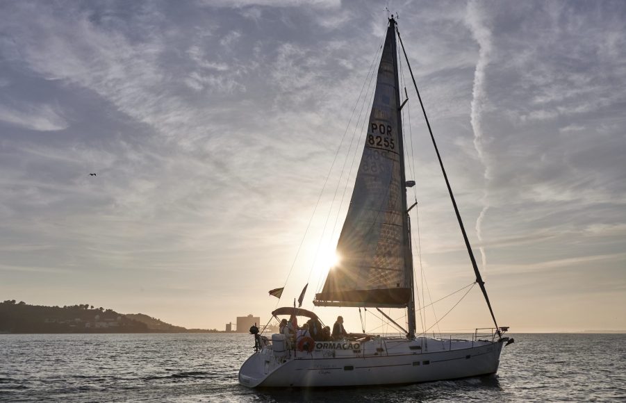 The sun sets behind a sailboat belonging to Escola de Navegação Treino de Mar (Navigation Training School of the Sea)