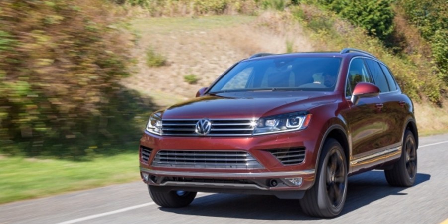 A brown Volkswagen Touareg midsize SUV is driving on the road.