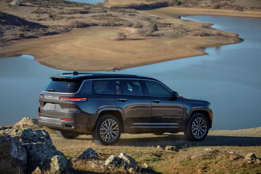 The rear 3/4 view of a brown 2021 Jeep Grand Cherokee L Summit Reserve by a desert lake