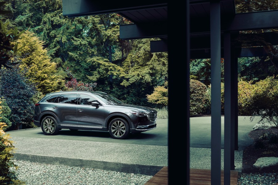 A metallic dark-gray 2021 Mazda CX-9 midsize crossover SUV sits in a home's driveway