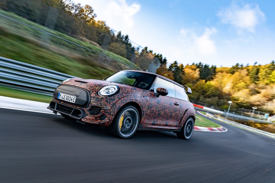 A 2021 Mini John Cooper Works zips around a paved track surrounded by rolling green hills and trees