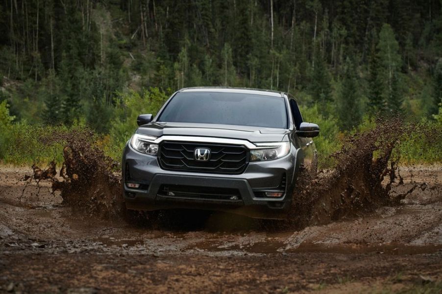 a 2021 honda ridgeline splashing through a muddy trailway in the forest