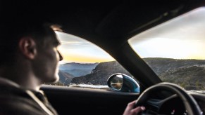 A young man driving a car through the mountains