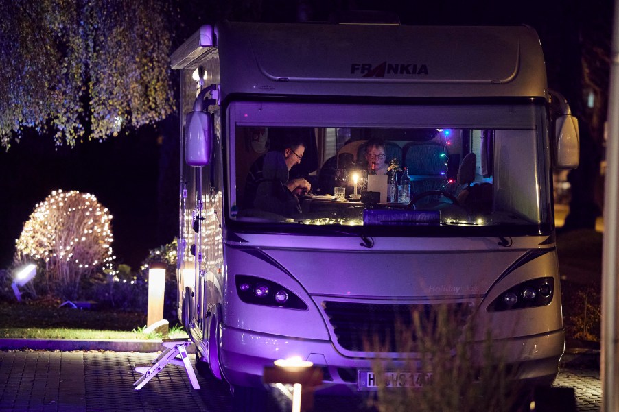 A couple enjoys the main dish of a four-course dinner in their recreational vehicle (RV) in the parking lot of the Kochschule Neumuenster cooking school