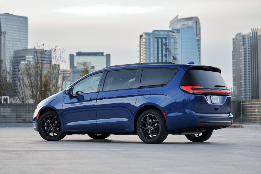 A blue 2021 Chrysler Pacifica Limited AWD S minivan parked in a lot with a cityscape in the background