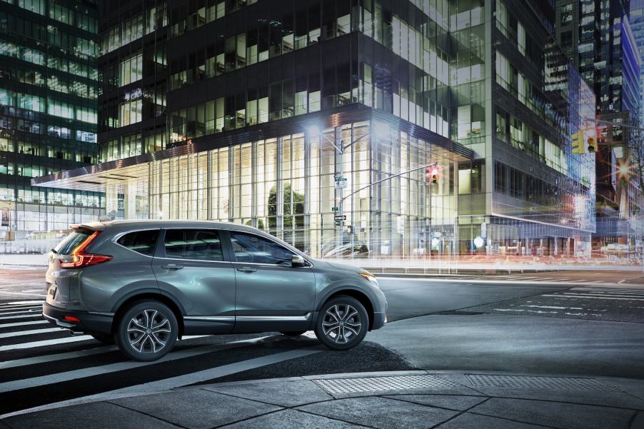 A grayish metallic 2021 Honda CR-V Touring model makes a right turn at a city intersection